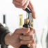 A drink bottle opener, specifically a Classic Wine Waiters Knife, is being used to remove a cork from a wine bottle.