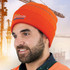 An orange hi-visibility beanie worn by a person, featuring a logo and set against a construction background.