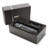 A sleek black and grey speaker packaged in a black box, complete with a cable inside. The box features branding.