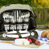 A grey picnic bag with cutlery, glasses, plates, and food items, set against a natural background.