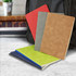 A collection of four notebooks in red, grey, brown, and green, positioned in front of a backpack.