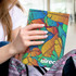 A large notebook featuring a vibrant, multicoloured leaf design and a logo on the front cover.