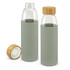 A drink bottle in soft green with a bamboo lid, featuring a glass body and a protective sleeve.