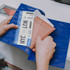 A blue vinyl travel wallet containing a passport and airline tickets. Hands are holding the wallet open.
