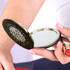 A compact mirror with a circular design, featuring a reflective surface and a dark exterior, held in a hand.