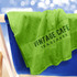 A bright green towel draped over a blue chair, featuring a logo on its surface.