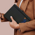 A large black hardcover notebook held by a person, featuring a design with an airplane and a logo.