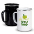 A set of enamel mugs in black and white, featuring a green apple design on the white mug and a handle.