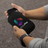 A black phone sleeve with a zip, held in a hand, featuring a multicoloured logo on the front.