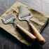 A metallic grater and slicer set with wooden handles on a green cloth napkin.