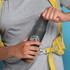 A drink bottle in matte black with a cork base, held by a person wearing a grey shirt and yellow backpack.
