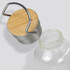 A drink bottle with a transparent glass body, topped with a rounded bamboo and metal lid, featuring a handle.