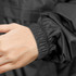 A close-up of a black soft shell windbreaker jacket sleeve with an elastic cuff. The jacket features a logo.
