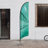A medium feather flag kit with a teal design, featuring a logo, set up outdoors.