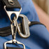 A silver carabiner multi-tool attached to a dark blue fabric bag, featuring a logo.