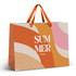 A large paper bag featuring orange, pink, and cream waves, with orange ribbon handles and a logo.