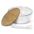 A glass food container with a wooden lid and a white elastic band. The container is clear and round.