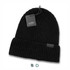 A black knitted beanie with a folded cuff and a tag attached, featuring a branding label.