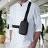 A black roll-top mini bag worn across the body over a white shirt, featuring a quilted pattern and an adjustable strap.