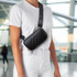 A black Rollink Mini Bag Tour worn across the body, featuring a diamond pattern, set against an airport backdrop.