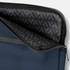 A navy soft-touch laptop sleeve features a grey zipper and a patterned interior lining. It includes branding.