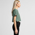 A cropped green t-shirt viewed from the side, featuring a simple design and a light fabric.