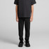 Youth track pants in black, featuring a relaxed fit and paired with a plain black t-shirt and shoes.