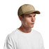 A beige soft cap worn by a person against a plain background. The cap features a logo.