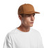 A brown canvas cap featuring a structured design and a logo, paired with a plain white T-shirt.
