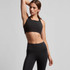 A black crop top with a square neckline, paired with high-waisted black leggings. The model is in a posed stance.