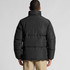 A puffer jacket in black, featuring a high collar and a puffy design from a rear view. It has a logo on the sleeve.