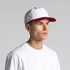 A two-tone cap featuring a white crown and a red peak, worn by a model in a plain white t-shirt.