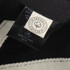 A black and grey cap made from organic cotton, featuring a tag with a logo and care instructions.