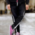 Custom women's sports pants in black with white and orange accents, featuring a relaxed fit and a drawstring waistband.