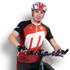 A male cyclist wearing a red and black custom cycling jersey and a helmet, positioned on a bicycle. The jersey features a logo.