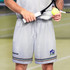 Light grey men's tennis shorts with a logo and striped detailing at the hem, held by a person with a tennis racquet and ball.
