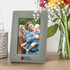 A grey photo frame featuring a family portrait, placed beside a lantern and vibrant flowers.