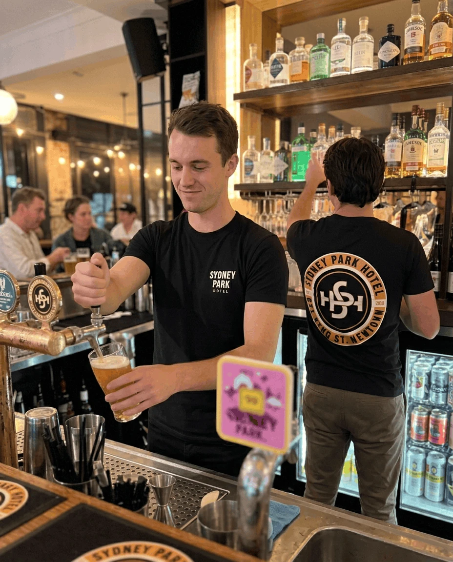 Staff in custom printed hotel and pub merchandise behind the bar