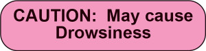 Pink rounded sticker with black text CAUTION May cause Drowsiness