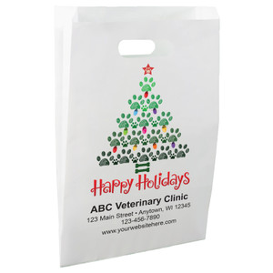White die-cut handle paper bag featuring a Christmas tree made of green paw prints, colorful holiday lights, a red paw print star, and the message "Happy Holidays".


