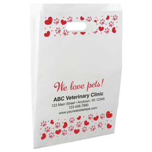 White die-cut handle paper bag featuring red hearts, pink paw prints, and the phrase "We love pets!" with matching top and bottom borders.


