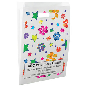 White die-cut handle paper bag featuring colorful paw prints, stars, and circular accents in a scattered multicolor pattern.
