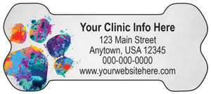 Bone-shaped veterinary die-cut magnet featuring a colorful paint splatter paw print on the left side with personalized clinic information on a gray background.

