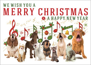 Holiday veterinary greeting card featuring singing dogs and cats beneath colorful Christmas music notes, ornaments, holly accents, and sheet music. The card displays the message “We Wish You a Merry Christmas & A Happy New Year” in festive red and green lettering.