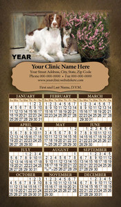 Personalized magnetic calendar featuring a brown and white dog and tabby cat beside pink flowers, rustic wooden background, parchment-style imprint area, and yearly calendar grid.


