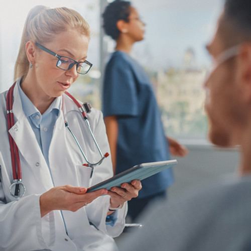 Female doctor talking with man in hospital bed