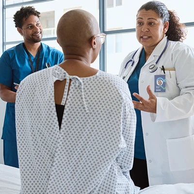 Doctor speaking to patient seated on hospital bed.