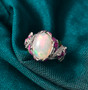 ethiopian opal and white zircon lotus flowering enamel ring in rhodium over sterling silver shown in a lifestyle photo