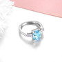 angled view of sky blue topaz and white zircon 3 stone ring in rhodium over sterling silver