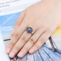 tanzanite round cluster ring in black and white rhodium over sterling silver worn on a hand